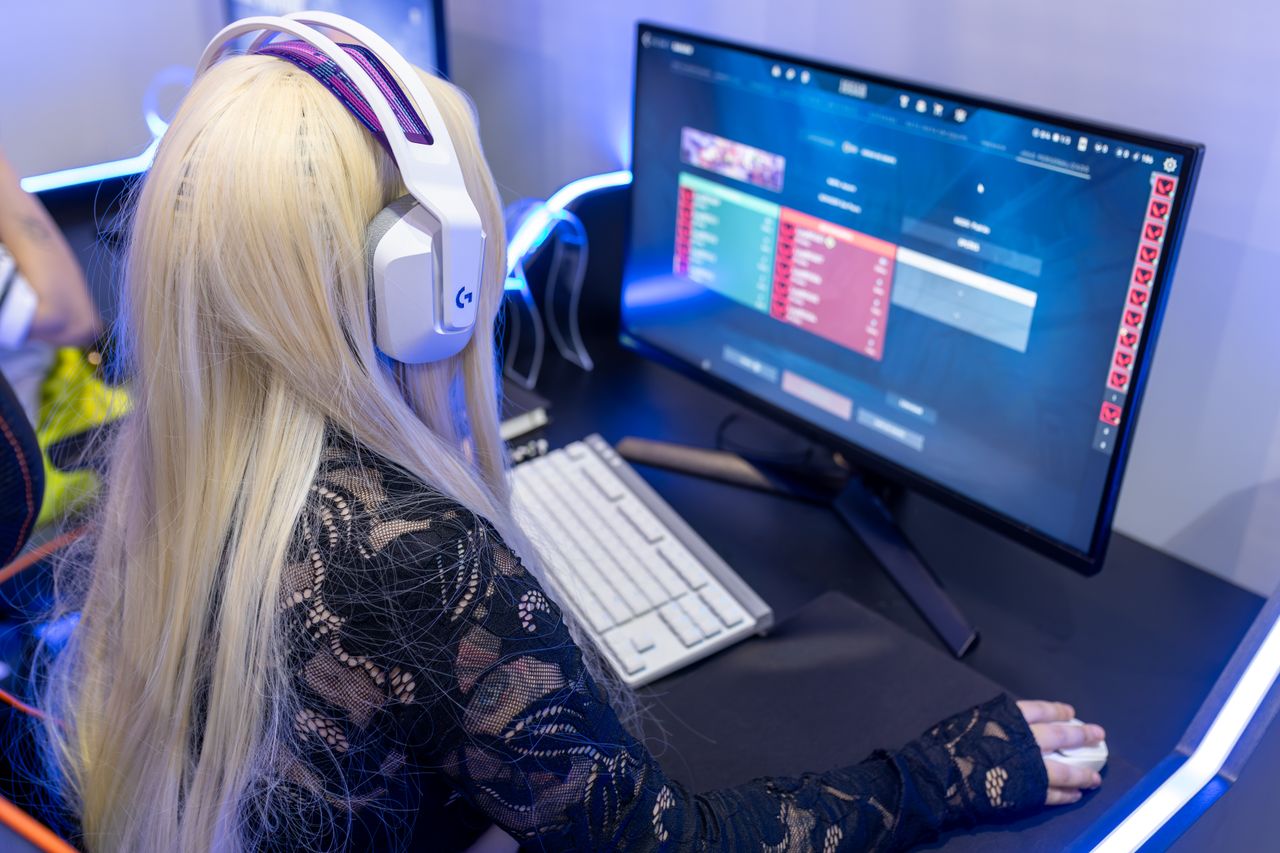 Young woman gaming at a PC high-tech setup, wearing headphones.
