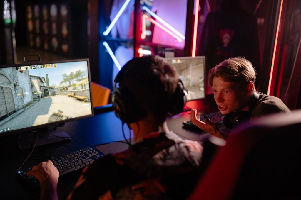 Two gamers engaged in a heated video game session surrounded by neon lights and computer screens.