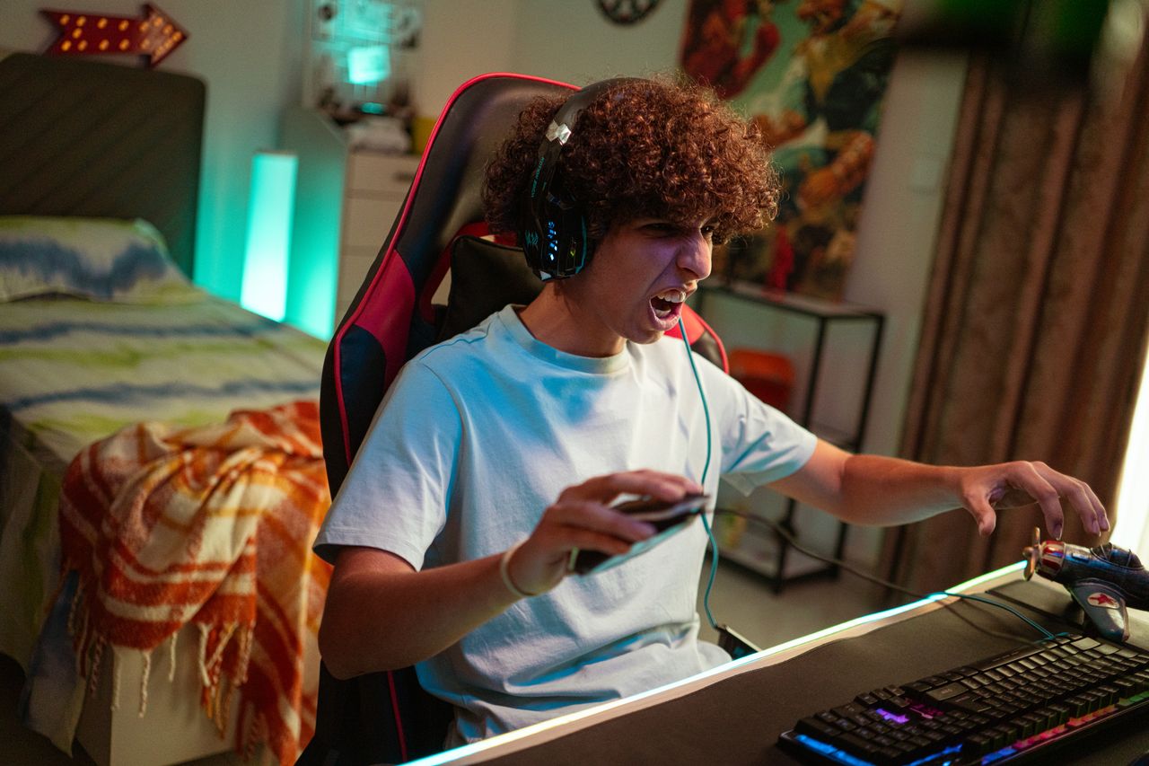 Teenager gaming at home, focused and excited in a modern gaming setup.